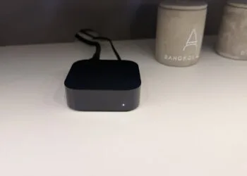 Apple TV 4K A19: black Apple TV box with glowing status light on a light shelf