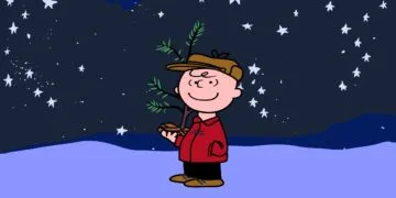 Charlie Brown holding a small Christmas tree under a starry sky in the snow, a scene from A Charlie Brown Christmas, free again on Apple TV