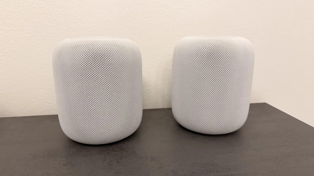 HomePod surround: two white HomePod speakers side by side on a dark countertop