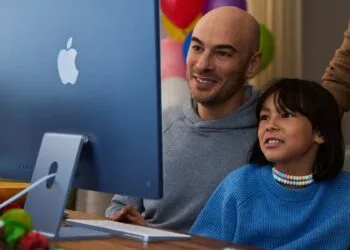 A child sits with an adult in front of a blue iMac, image for Apple's guide on family screen time