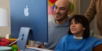 A child sits with an adult in front of a blue iMac, image for Apple's guide on family screen time