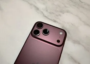 Close-up of the camera system of a burgundy iPhone 18 Pro Max on light marble – the main camera the iPhone 18 Pro uses for Cinematic mode effects and 4K time-lapse