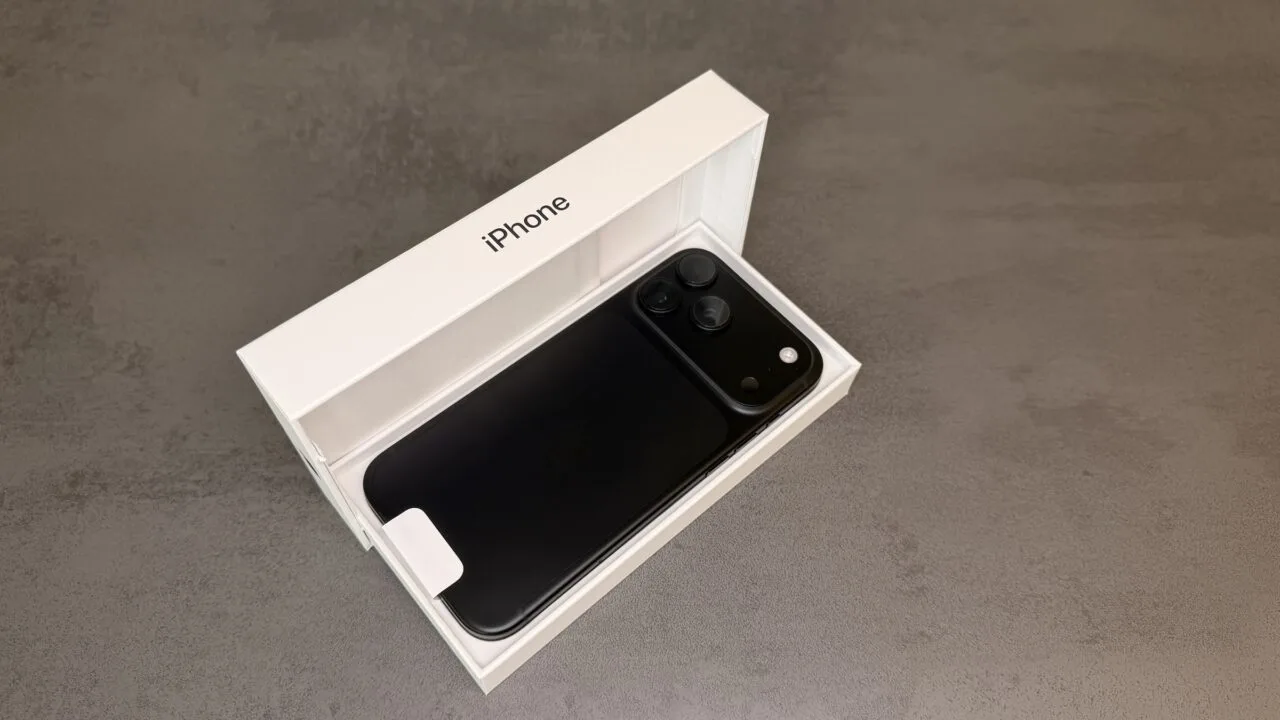 Black iPhone 18 Pro Max lying face down in its open original box on a grey stone surface