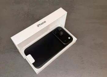 Black iPhone 18 Pro Max lying face down in its open original box on a grey stone surface