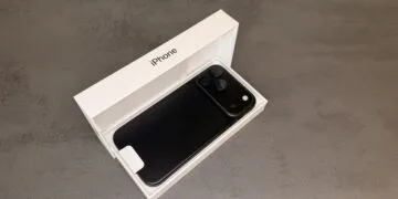 Black iPhone 18 Pro Max lying face down in its open original box on a grey stone surface