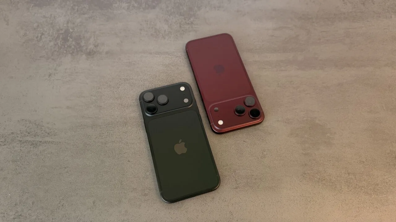 Two iPhone 18 Pro Max in black and burgundy seen from the back on a grey stone surface, focusing on the camera system with the variable aperture main camera