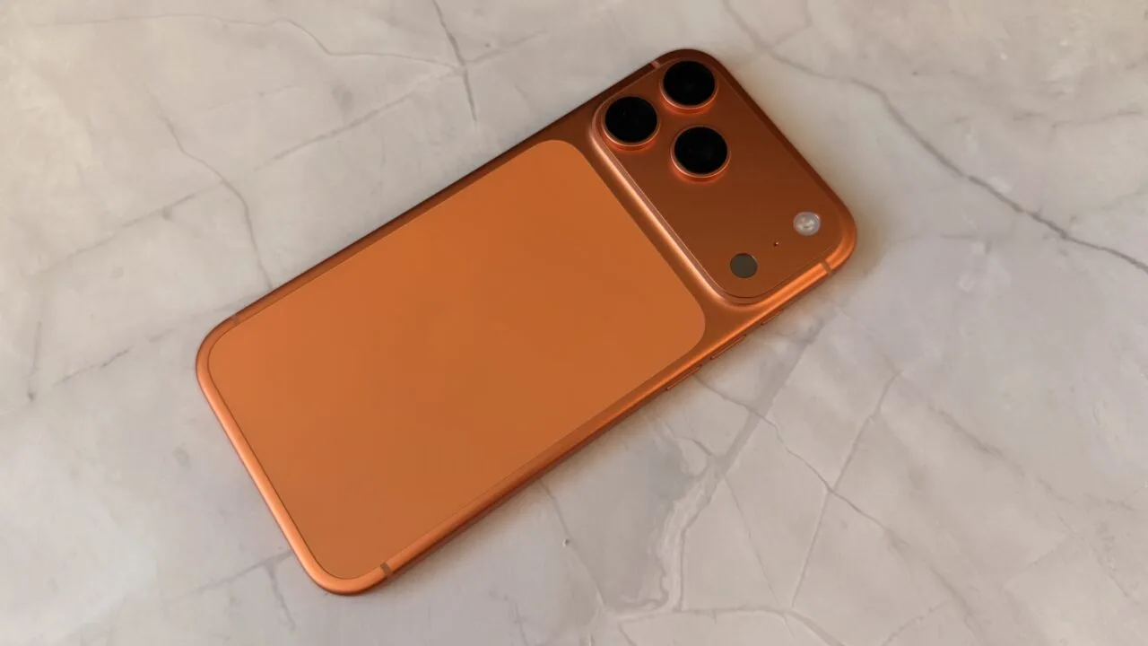 iPhone storage 2027: back of an orange iPhone with a triple camera on a light marble surface