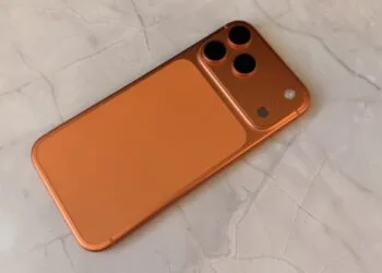 iPhone storage 2027: back of an orange iPhone with a triple camera on a light marble surface