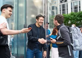 John Ternus shakes hands with a customer outside Apple Fifth Avenue in New York, surrounded by applauding employees