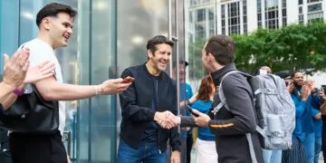John Ternus shakes hands with a customer outside Apple Fifth Avenue in New York, surrounded by applauding employees