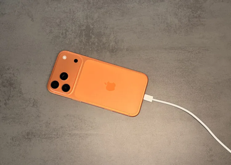 iPhone in an orange case connected to a USB-C cable, the starting point for juice jacking at unknown ports