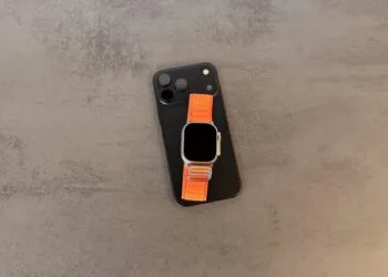 Taptic Engine in iPhone and Apple Watch: black iPhone with triple camera and an Apple Watch Ultra with an orange Alpine Loop on top
