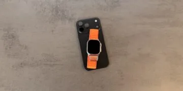 Taptic Engine in iPhone and Apple Watch: black iPhone with triple camera and an Apple Watch Ultra with an orange Alpine Loop on top