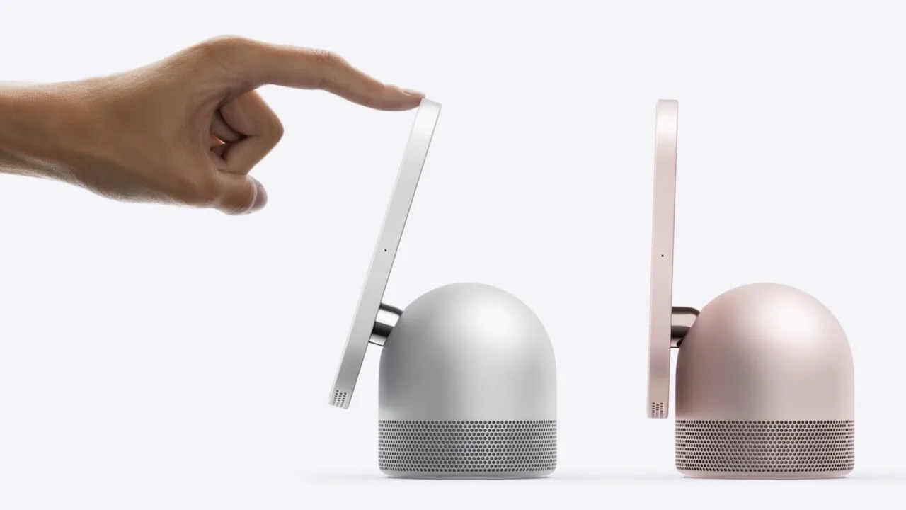 HomeView robotic arm: a hand tilts the display of a silver HomeView with one finger, next to it stands a second model in pink