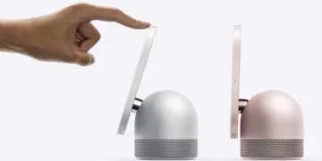 HomeView robotic arm: a hand tilts the display of a silver HomeView with one finger, next to it stands a second model in pink