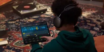 Apple Samplab: person wearing headphones editing an audio track split into slices in Logic Pro on iPad, with a turntable in the background