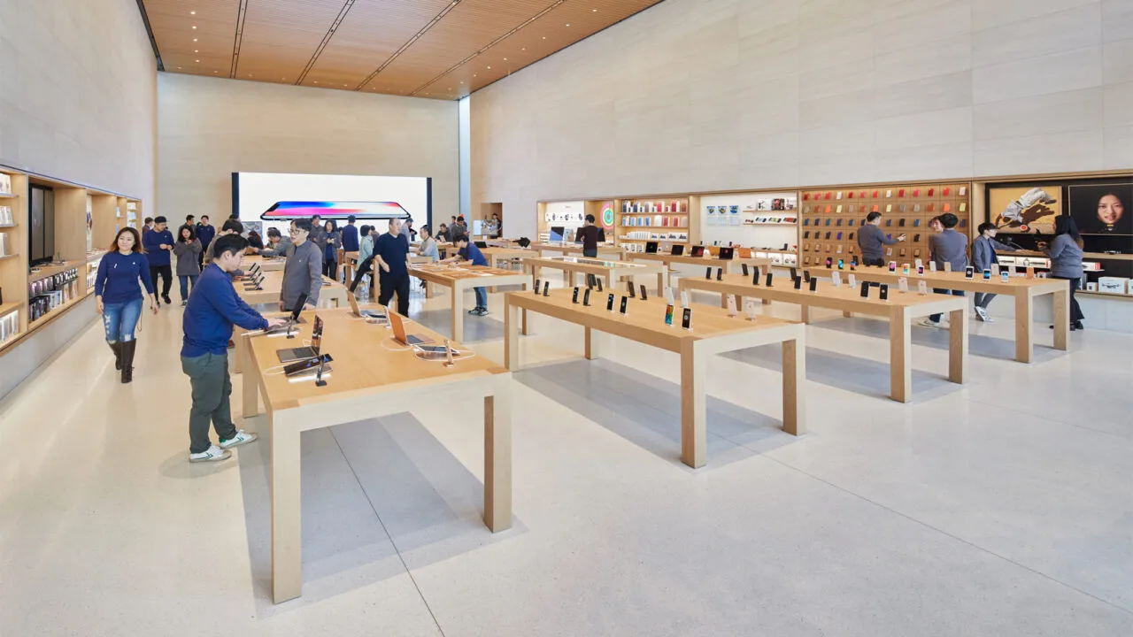 Sales floor of an Apple Store with wooden tables, iPhones on display and team members, where an iPhone return at the Apple Store is handled