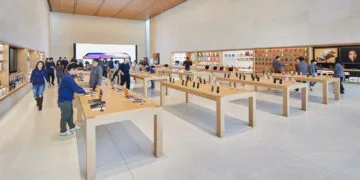 Sales floor of an Apple Store with wooden tables, iPhones on display and team members, where an iPhone return at the Apple Store is handled