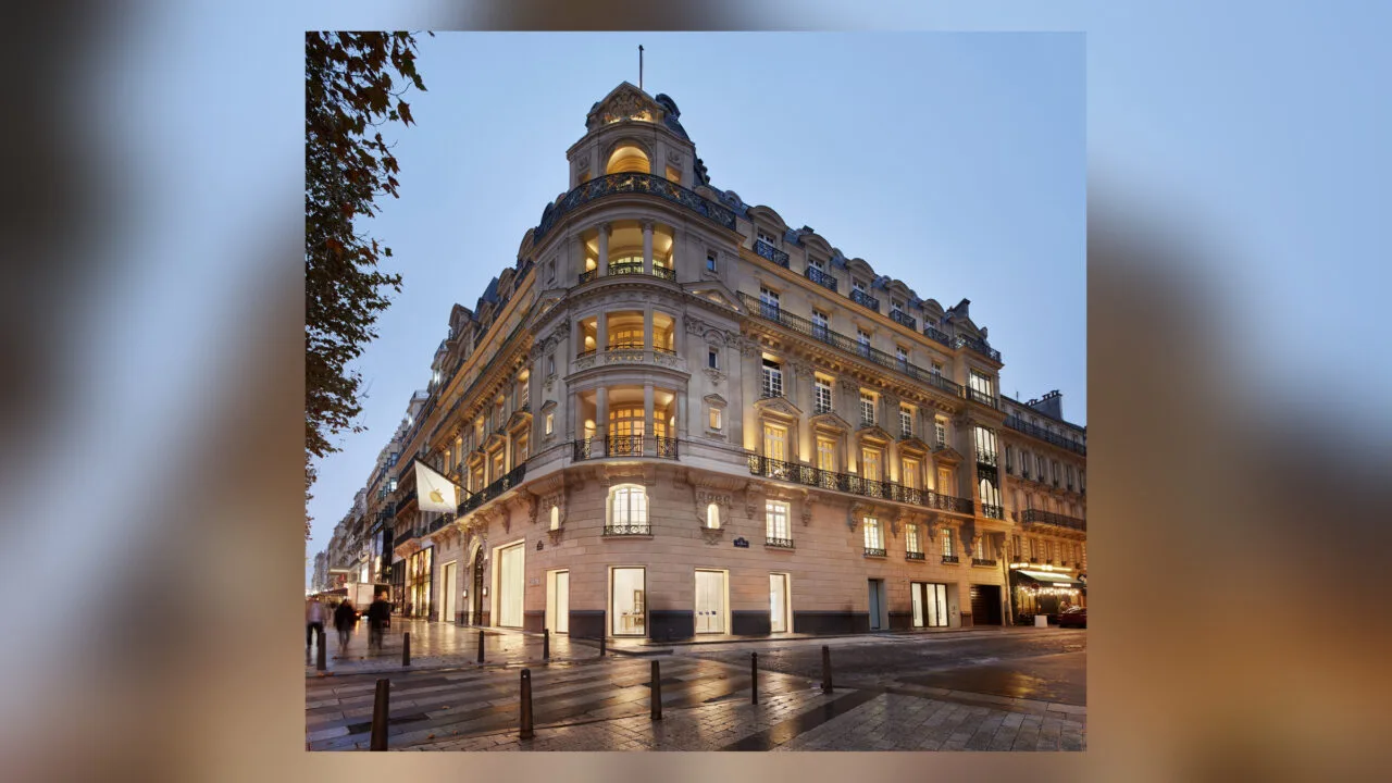 One of the Apple Stores in France: the Champs-Élysées location in Paris in an illuminated corner building with an Apple flag in the evening.