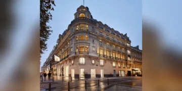 One of the Apple Stores in France: the Champs-Élysées location in Paris in an illuminated corner building with an Apple flag in the evening.