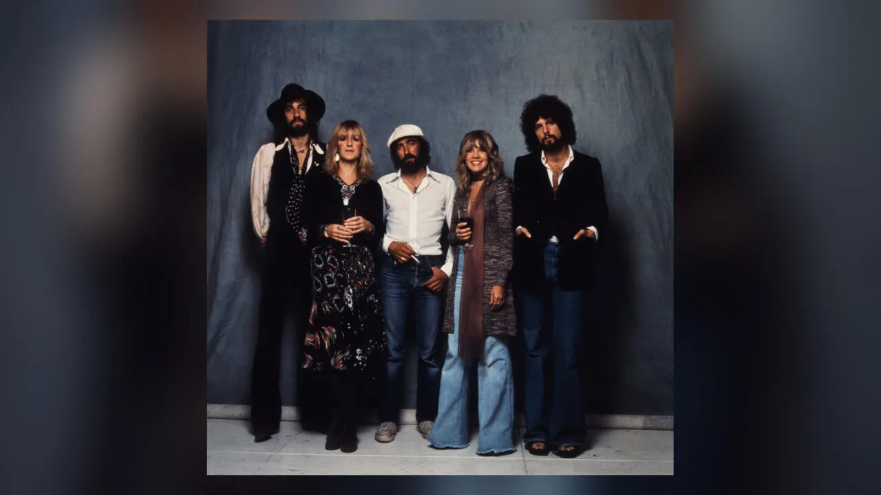 The five members of Fleetwood Mac standing side by side in front of a blue backdrop, band photo for the Fleetwood Mac documentary on Apple TV