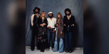 The five members of Fleetwood Mac standing side by side in front of a blue backdrop, band photo for the Fleetwood Mac documentary on Apple TV