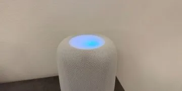 White HomePod with its top glowing in shades of blue and violet in front of a light wall – this is what HomePod Sound Glow looks like