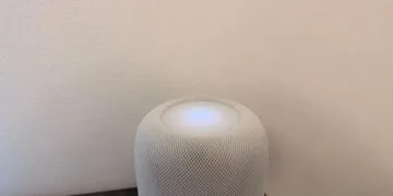 Lock HomePod touch controls: white HomePod with an illuminated touch surface and plus and minus symbols in front of a light wall