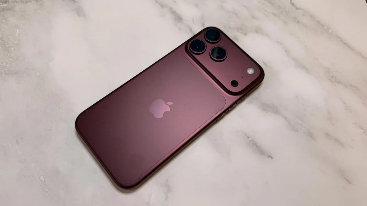 iPhone China market share: a dark red iPhone from the Pro lineup seen from the back on a light marble surface, with camera plateau and three lenses