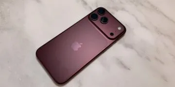 iPhone China market share: a dark red iPhone from the Pro lineup seen from the back on a light marble surface, with camera plateau and three lenses