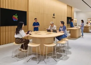 Symbolic image for iPhone China: Apple Store with wooden walls, customers working on iPads at a table next to a staff member