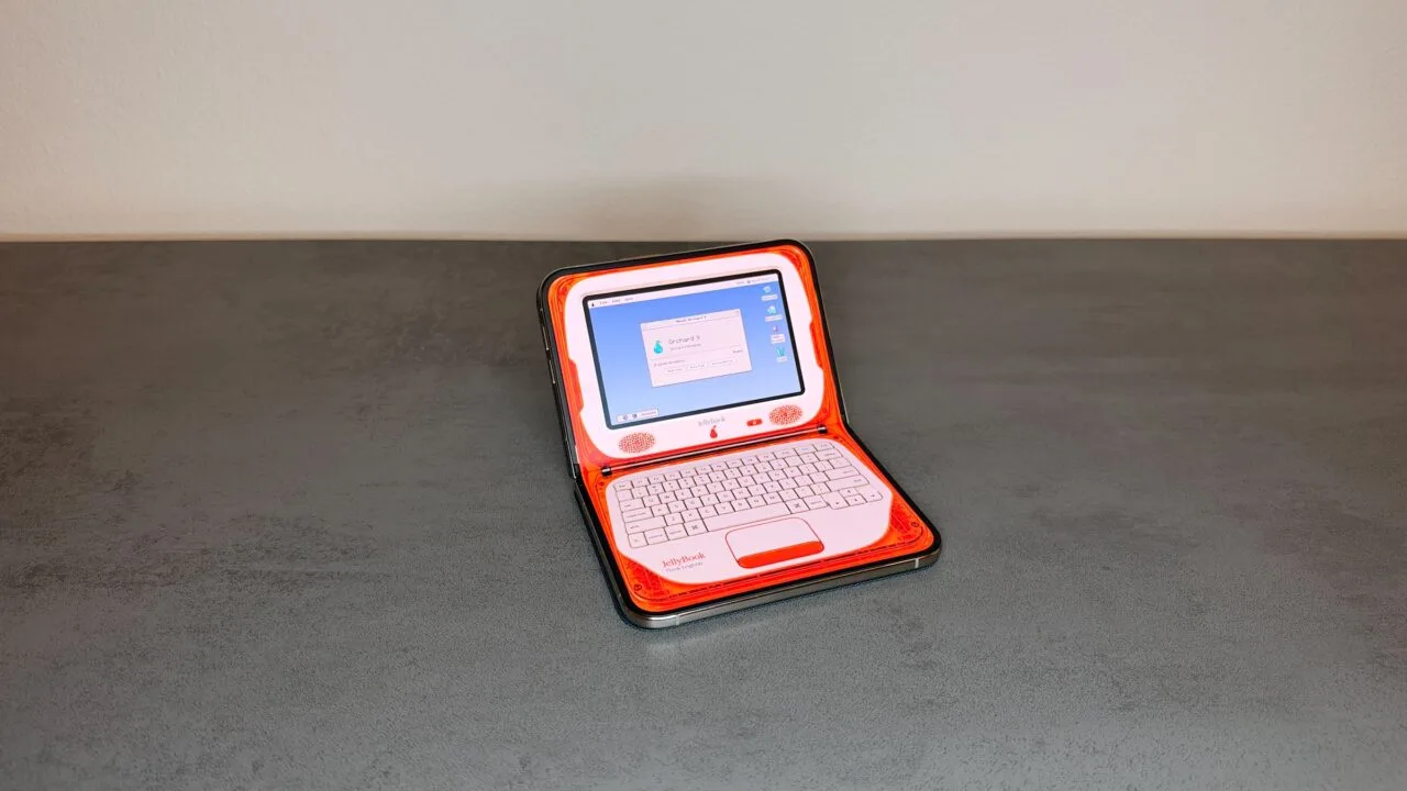 One of the adapted iPhone Duo apps turns the half-folded iPhone Duo on a table into an orange retro laptop with the screen on top and the keyboard below.
