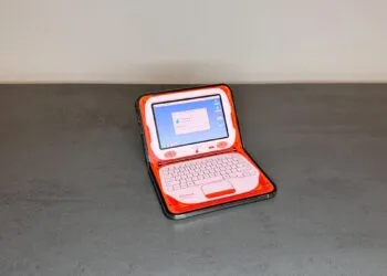 One of the adapted iPhone Duo apps turns the half-folded iPhone Duo on a table into an orange retro laptop with the screen on top and the keyboard below.