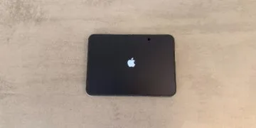 iPhone Duo recall: unfolded iPhone Duo lying flat on a grey table, the inner display showing the Apple logo during startup
