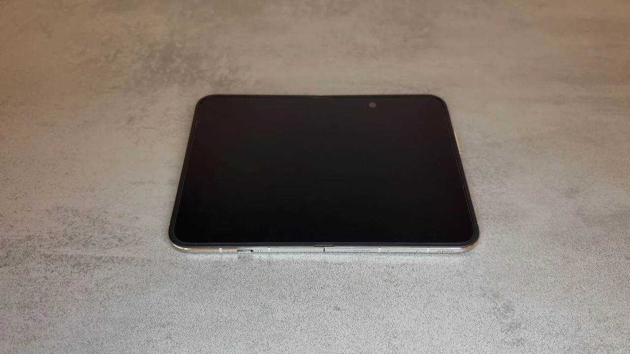 iPhone Duo inner display: the unfolded iPhone Duo lies flat on a grey table with its display switched off