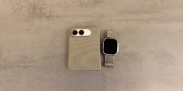 Unlocking iPhone Duo with Apple Watch: folded iPhone Duo in a case, camera side up, next to an Apple Watch Ultra with a mesh band on a grey stone surface