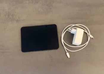 iPhone Duo fast charging: an unfolded iPhone Duo on a gray stone surface next to a white USB-C power adapter and a braided USB-C charging cable