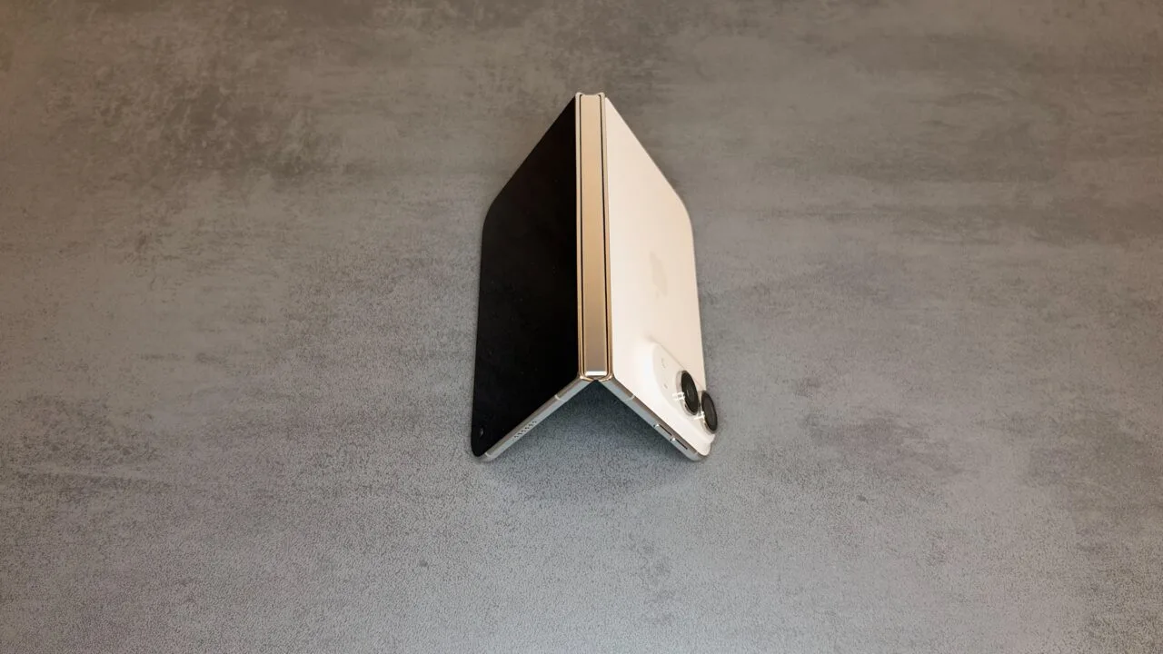 iPhone Duo teardown: half-open iPhone Duo in Star White, standing like a tent, with the hinge in the center of the image