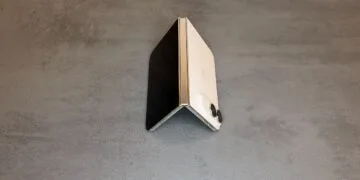 iPhone Duo teardown: half-open iPhone Duo in Star White, standing like a tent, with the hinge in the center of the image