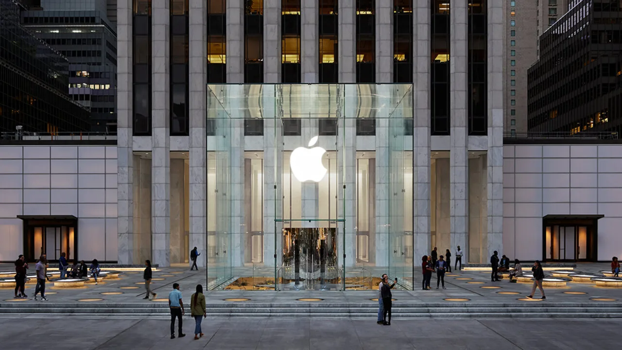 The Apple Store on Fifth Avenue in New York, set to receive more than 150 iPhone Duo demo units: the glass cube with its illuminated Apple logo in front of the tower at dusk
