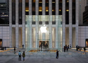 The Apple Store on Fifth Avenue in New York, set to receive more than 150 iPhone Duo demo units: the glass cube with its illuminated Apple logo in front of the tower at dusk