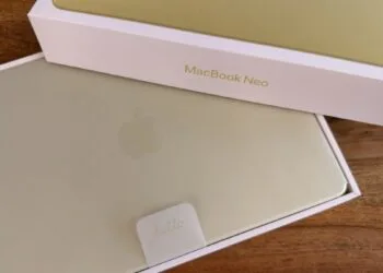 Freshly unboxed yellow MacBook Neo with hello tab in its box on a wooden table – illustrating Mac shipments in the third quarter