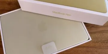 Freshly unboxed yellow MacBook Neo with hello tab in its box on a wooden table – illustrating Mac shipments in the third quarter