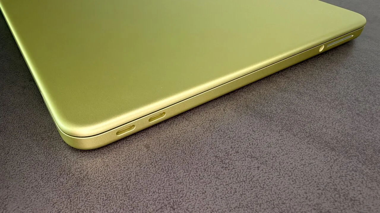 Closed MacBook Neo in Citrus with two USB-C ports on a dark tabletop, on the rising Mac market share in a shrinking PC market
