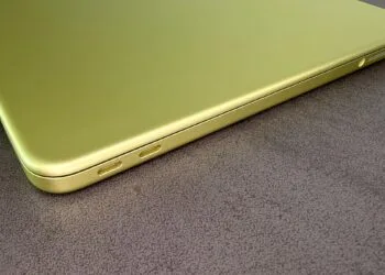 Closed MacBook Neo in Citrus with two USB-C ports on a dark tabletop, on the rising Mac market share in a shrinking PC market
