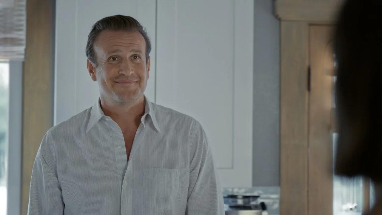Ahead of Shrinking season 4: Jason Segel as Jimmy in an earlier episode, smiling in a kitchen, a blurred person in the foreground on the right