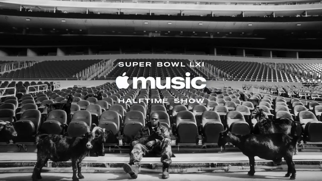 Super Bowl LXI Jay-Z: the rapper sits in camouflage clothing on an empty stadium stand among black goats, below the Apple Music Halftime Show logo